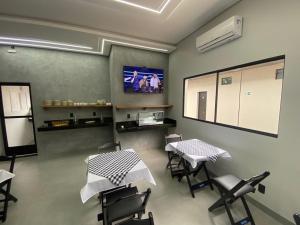 a waiting room with two tables and chairs and a screen at Village Prime Hotel in Miguelópolis
