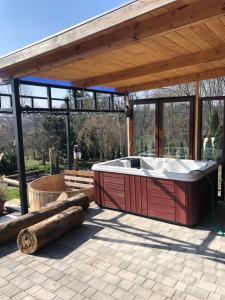 a hot tub sitting under a pavillion with a wooden roof at Ranczo Borówka in Łapanów
