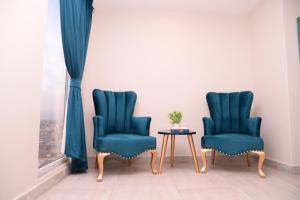 duas cadeiras azuis e uma mesa num quarto em Tom's Luxury em Peshawar