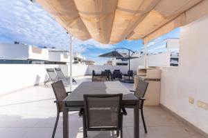 a patio with a table and chairs on a roof at Arenales Bahia Penthouse in Arenales del Sol