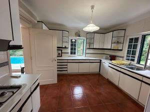 eine Küche mit weißen Schränken und braunen Fliesenböden in der Unterkunft Golf, Pool and Beach Aroeira Villa in Aroeira