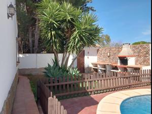 płot obok basenu z palmą w obiekcie Chalet con piscina privada en Conil Solo Familias w mieście Conil de la Frontera