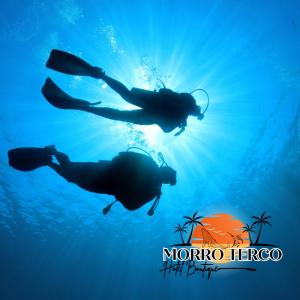 dos personas nadando en el océano con el sol detrás de ellos en Morro Terco Hotel Boutique en Nuquí