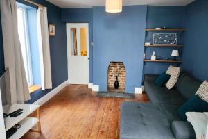 ein blaues Wohnzimmer mit Sofa und Kamin in der Unterkunft Quaint 3 bedroom Devon cottage in Honiton