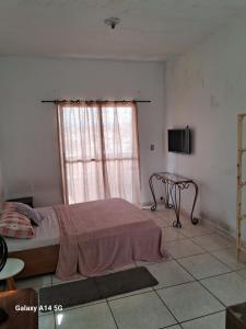 聖保羅的住宿－Kit com varanda，一间卧室配有一张床、一张桌子和一个窗户。