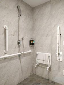 a shower in a bathroom with white tiles at Happy Inn in Taichung