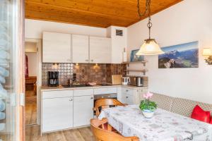 a kitchen with white cabinets and a table with a table cloth at Häuserl in Garmisch-Partenkirchen