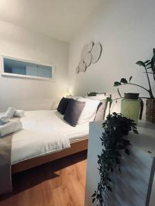 een slaapkamer met een bed met witte lakens en een plant bij Km Style Apartment Nr 1 in Freiburg im Breisgau