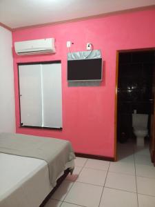 Cette chambre est dotée d'un mur rouge avec un lit et des toilettes. dans l'établissement HOTEL AL MARE ATLANTICO, à Aracaju