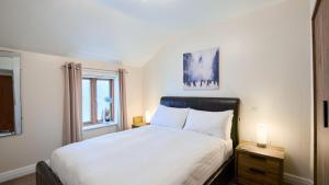 a bedroom with a large white bed and a window at Lake District Apartment At Windermere Marina Village in Bowness-on-Windermere