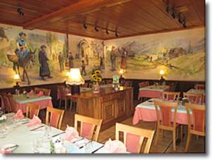 ein Restaurant mit Tischen, Stühlen und Gemälden an der Wand in der Unterkunft Au Manoir d'Anniviers in Vissoie