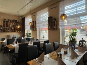 un comedor con mesas, sillas y ventanas en Alte Schmiede Hotel & Restaurant en Jork