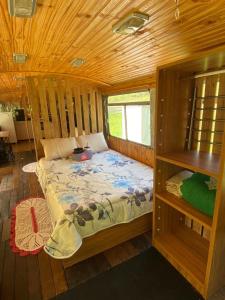 a bedroom with a bed in a wooden cabin at Chalé Bus Ponto Z in São Bento do Sapucaí