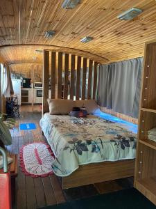 a bedroom with a large bed with a wooden ceiling at Chalé Bus Ponto Z in São Bento do Sapucaí