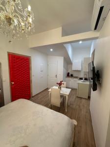 een kamer met een rode deur, een tafel en een keuken bij Petit studio presbytère dans L'Église in Narbonne