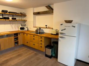 eine Küche mit einem weißen Kühlschrank und Holzschränken in der Unterkunft Willkommen im Alpen Relax in Obergünzburg