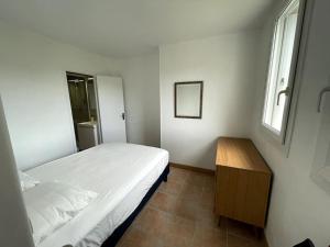 Habitación pequeña con cama y mesa de madera. en Charmant logement avec parking privé., en Veules-les-Roses