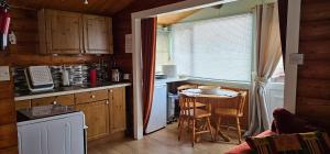 una cucina con un tavolino e una cucina con finestra di Snowdonia National park Log cabin with garden a Trawsfynydd
