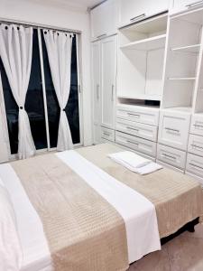 a white bedroom with a large bed and a tv at Hermosa casa en Bucaramanga in Bucaramanga