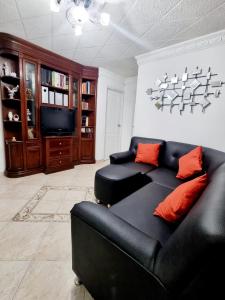 a living room with a black couch and a television at Hermosa casa en Bucaramanga in Bucaramanga