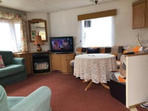 a living room with a table and a tv at 2 bedroom static caravan in Muirkirk