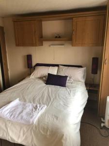 een bed met witte lakens en kussens in een slaapkamer bij 2 bedroom static caravan in Muirkirk