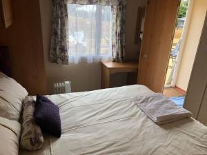 een slaapkamer met een wit bed en een raam bij 2 bedroom static caravan in Muirkirk