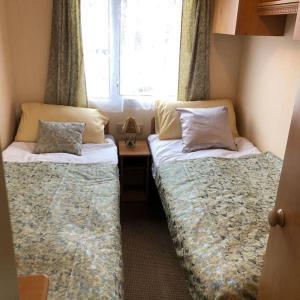 a bedroom with two beds and a desk with a window at 2 bedroom static caravan in Muirkirk