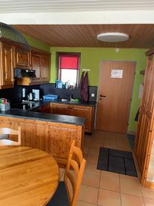 cocina con armarios de madera, mesa y puerta en Apartment sunny mountains Gerlitzen, en Deutschberg