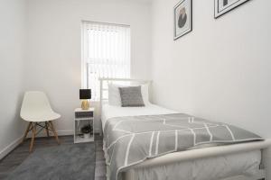 a white bedroom with a bed and a chair at Perfect Modern 4 bedroom in Liverpool in Liverpool