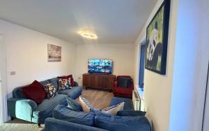 un salon avec des canapés bleus et une télévision dans l'établissement Bracknell Contemporary Stylish 3 bedroom in, à Bracknell