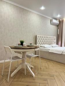 a bedroom with a bed and a table with chairs at Байзакова 133 in Pavlodar