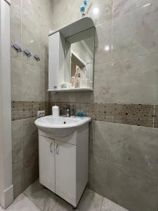 a bathroom with a white sink and a mirror at Байзакова 133 in Pavlodar