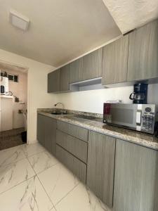 a kitchen with gray cabinets and a counter with a microwave at Departamento con vista al mar in Mazatlán