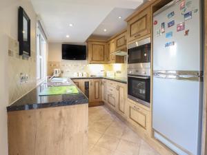 a kitchen with wooden cabinets and a white refrigerator at May Cottage in Llanfyllin