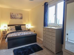 a bedroom with a bed and a dresser and a window at May Cottage in Llanfyllin