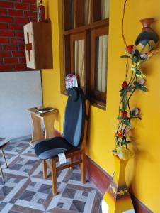 a yellow room with a blue chair and a vase at Casa Abuelito's Andean Haven in Huaraz