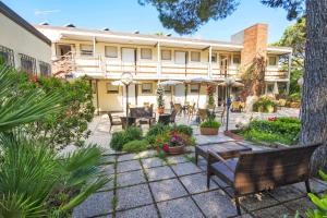 eine Terrasse mit Bänken und Tischen vor einem Gebäude in der Unterkunft Residence Casa Di Caccia in Marina di Bibbona