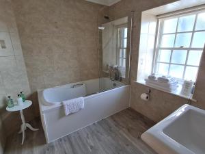 a white bathroom with a tub and a sink at Tarrel Farmhouse in Portmahomack