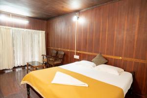 a bedroom with a large bed with a yellow blanket at Garggi Backwater Retreat in Kottayam