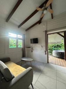 een woonkamer met een plafondventilator en een bank bij L'EdenKrys 2 avec son jacuzzi in La Trinité