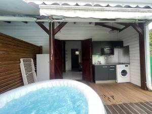 een hot tub op een patio met een keuken en een wasmachine bij L'EdenKrys 2 avec son jacuzzi in La Trinité