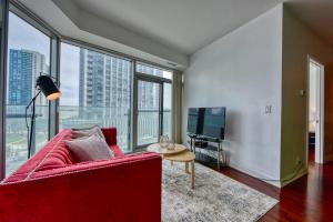 een woonkamer met een rode bank en een groot raam bij Downtown Apartments 16 in Toronto