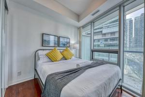 多倫多的住宿－Downtown Apartments 16，一间卧室配有一张带黄色枕头的床和一扇窗户