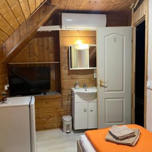 a bathroom with a sink and a tv in a room at Lenzl's Panzió in Szigetvár