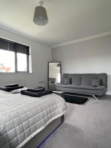 Modern 2 Bedroom House, Edinburgh. في Millerhill: غرفة نوم بيضاء مع سرير وأريكة