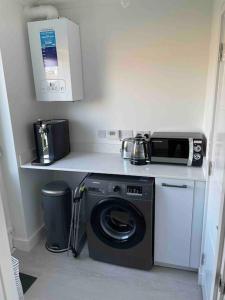 a kitchen with a washing machine and a microwave at Modern 2 Bedroom House, Edinburgh. in Millerhill