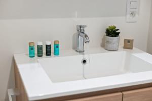a white bathroom sink with four bottles on it at Huswell - Apartment with natural swimming pool in Middelkerke