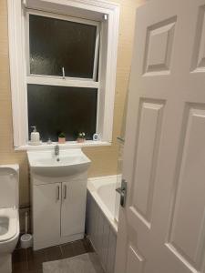 ein Bad mit einem Waschbecken, einem WC und einem Fenster in der Unterkunft Warm Chiltern House in Luton