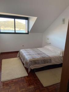 Schlafzimmer mit einem Bett und einem Fenster in der Unterkunft Mar de Muros - Piso 1ª línea de playa en Muros in Muros